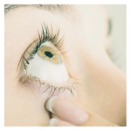 Close-up of an eye with a finger gently pulling down the lower eyelid, possibly preparing for eye drops.