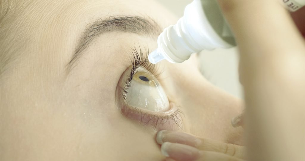 Close-up of an eye receiving drops from a dropper, emphasising hydration or relief for dry eyes.