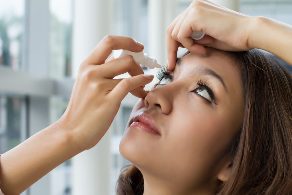 a woman putting eye drops into her eye